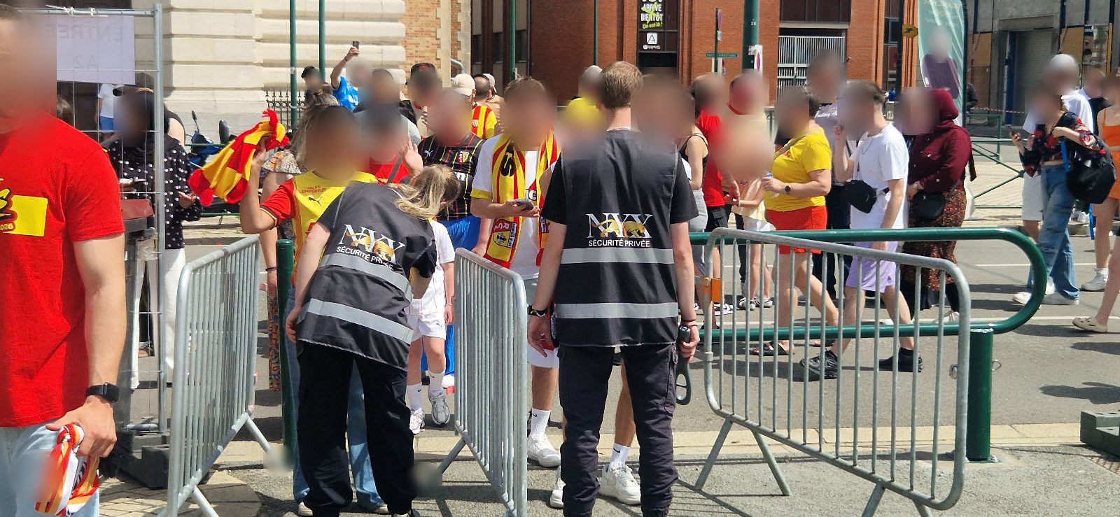 Agents NYX Sécurité Privée au point de filtrage avec barrières et supporters lensois en maillots Sang et Or, Coupe de France 2026